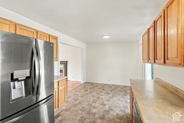 Kitchen featuring wood cabinetry, stainless steel French door refrigerator, laminate countertops, and tile-patterned flooring