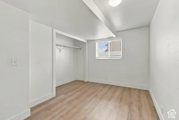 Interior room featuring wood-finish flooring, a built-in closet with integrated shelving, and a horizontal sliding window