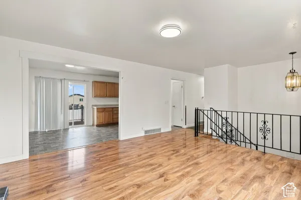 Open floor plan featuring wood-finish flooring, decorative wrought-iron railing, flush-mount ceiling lighting, and a hanging pendant fixture