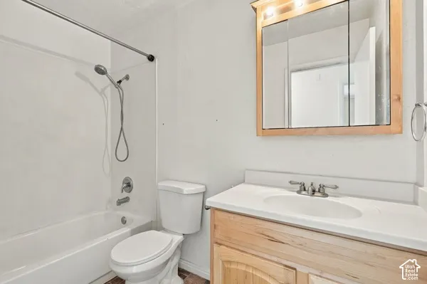 Bathroom featuring a wood-finish vanity with a white countertop, oval drop-in sink, and triple-mirror medicine cabinet, alongside a tub-shower combination with a handheld showerhead