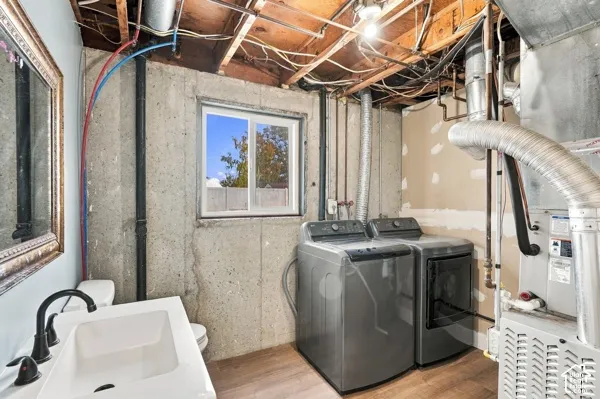 Utility space featuring a concrete foundation, a dual-pane sliding window, a modern rectangular vessel sink with a matte black faucet, and wood-finish flooring