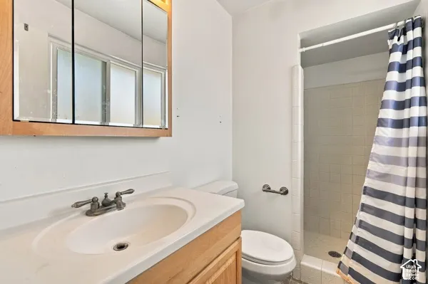 Bathroom featuring a light wood vanity with a solid-surface integrated sink, tri-panel medicine cabinet, and a tiled shower stall