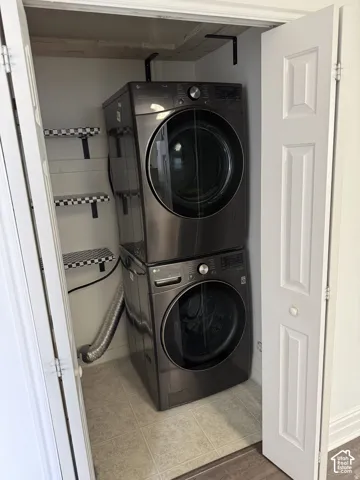 Laundry closet featuring stacked front-load appliances and integrated wall-mounted shelving