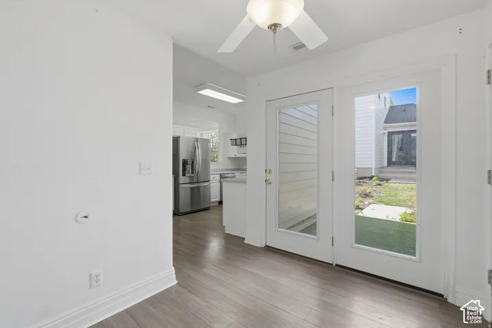 Wood-finish flooring, white double glass-panel doors, and a ceiling fan with integrated lighting