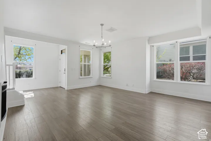 Open-concept interior featuring wood-finish flooring, multi-pane windows, crown molding, and a central chandelier