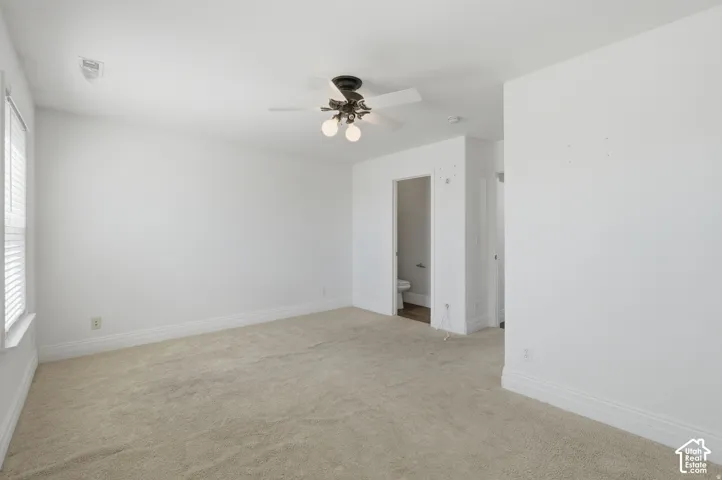 Neutral-toned wall-to-wall carpeting, ceiling fan with integrated lighting, and multi-pane window with white blinds