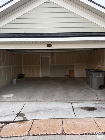 Two-car garage featuring a concrete floor, gabled roofline with horizontal lap siding, and a dedicated entry door