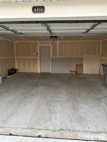 Two-car garage featuring a concrete floor, an automated overhead door, and an interior access door