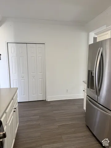Wood-finish flooring, stainless steel French-door refrigerator, and white bi-fold closet doors