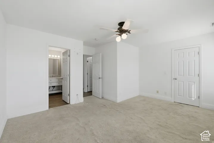 Neutral wall color, wall-to-wall carpeting, multi-panel doors, and a ceiling-mounted light fixture with a fan