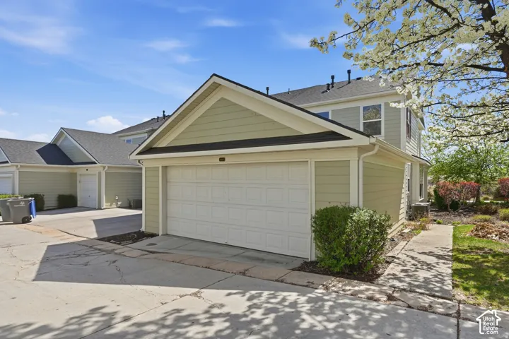 Two-story exterior featuring light-toned horizontal siding, a gabled roofline, and an attached single-car garage with a concrete driveway