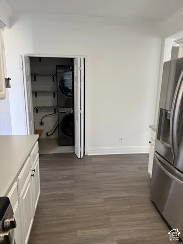 Kitchen area featuring wood-finish flooring, white cabinetry, solid surface countertops, and a laundry closet with shelving
