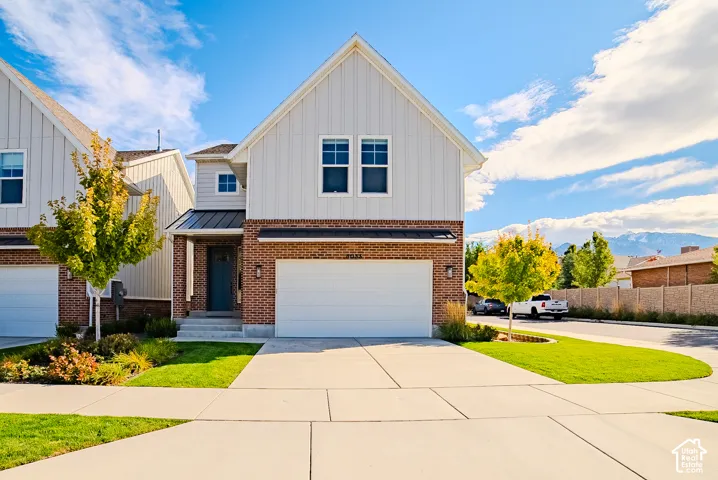 Two-story exterior featuring a mix of vertical siding and brick masonry, a metal roof accent, and an attached two-car garage