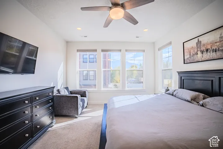 Neutral-toned carpeted flooring, multi-pane windows with integrated blinds, and a ceiling-mounted light fixture with a fan