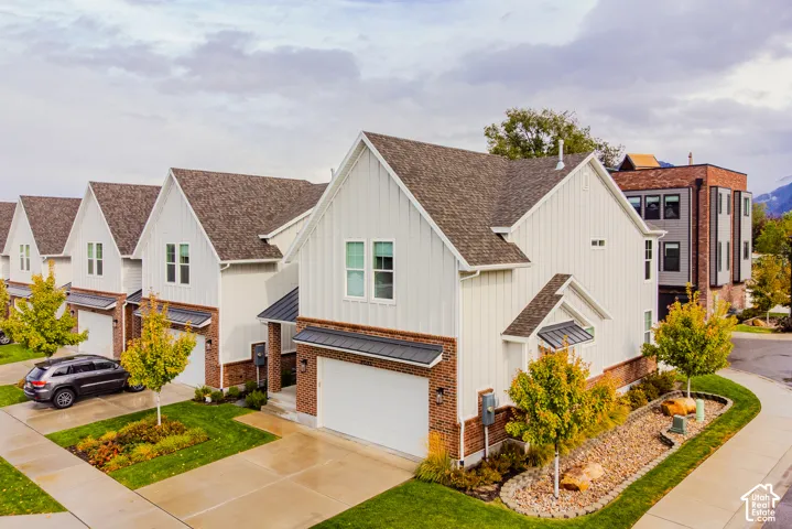 Two-story exterior featuring board-and-batten siding, brick masonry, asphalt shingle roofing, and an attached two-car garage