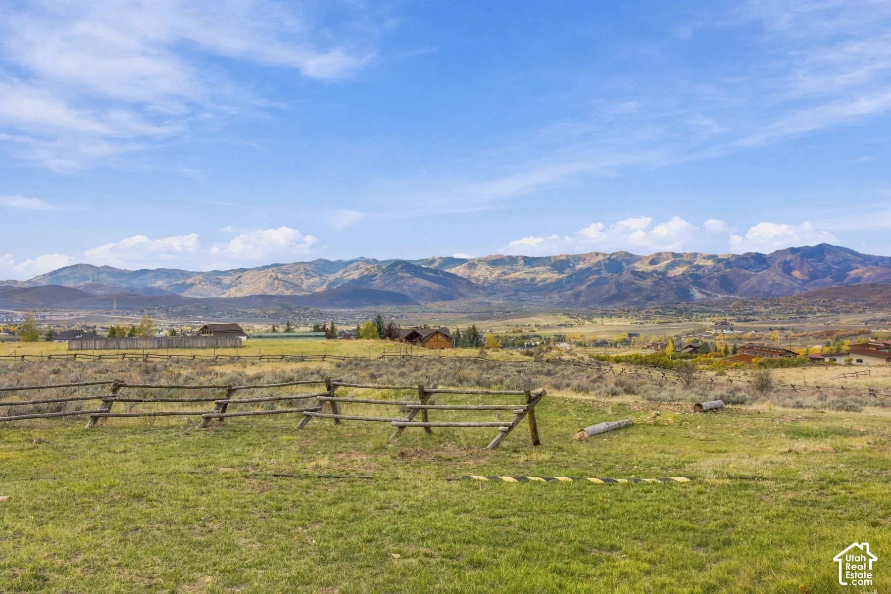 Open acreage featuring a post-and-rail timber fence and a mountain range backdrop