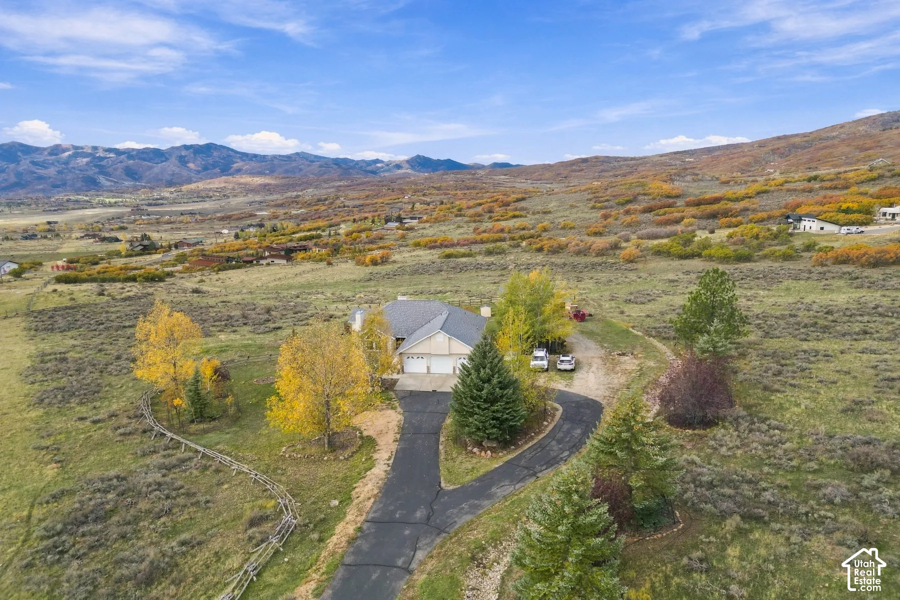 Detached single-story residence featuring an asphalt driveway, multi-car garage, and mountain backdrop