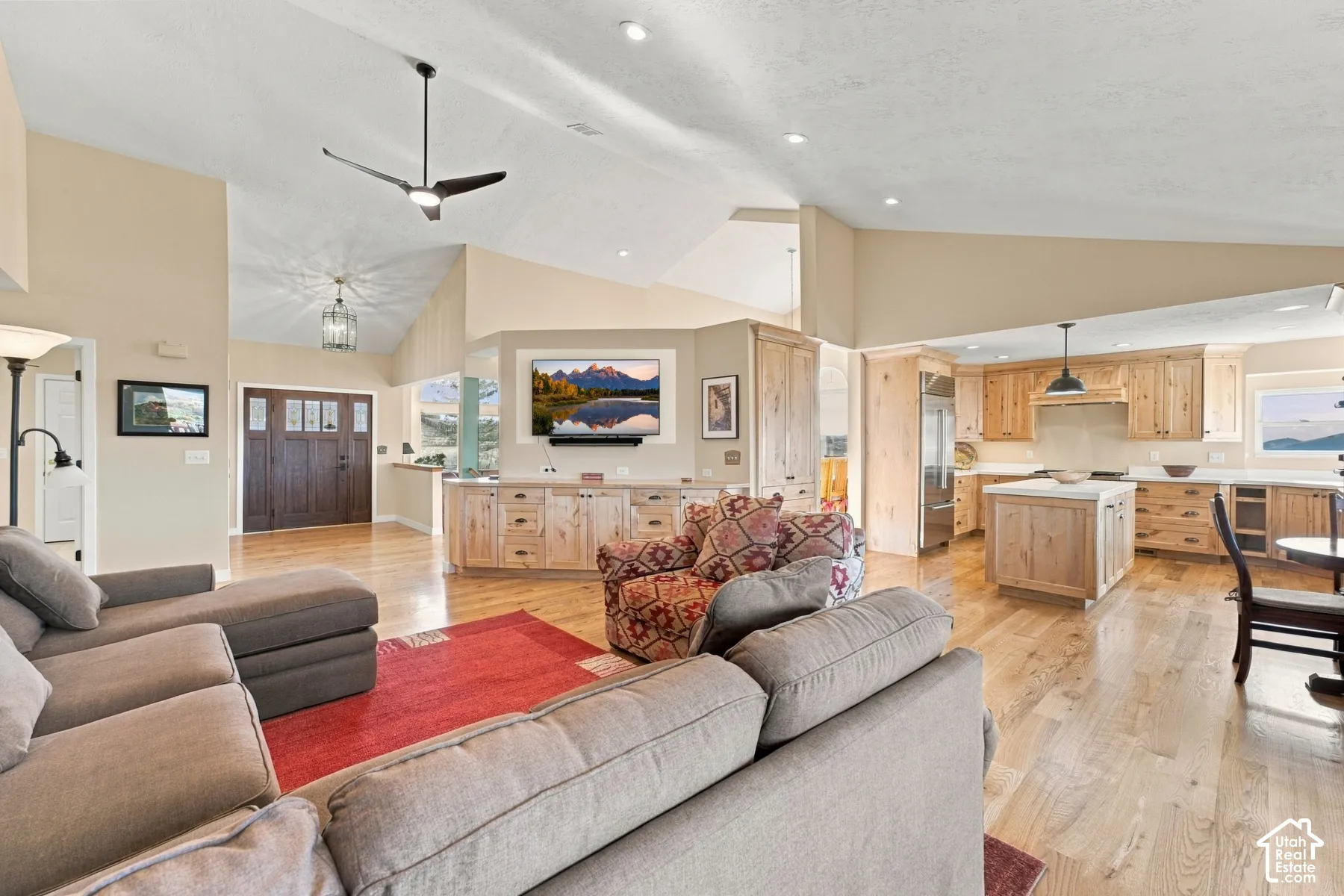 Vaulted ceilings with recessed lighting, wood-finish flooring, custom built-in cabinetry, center kitchen island, and multi-pane wood entry door