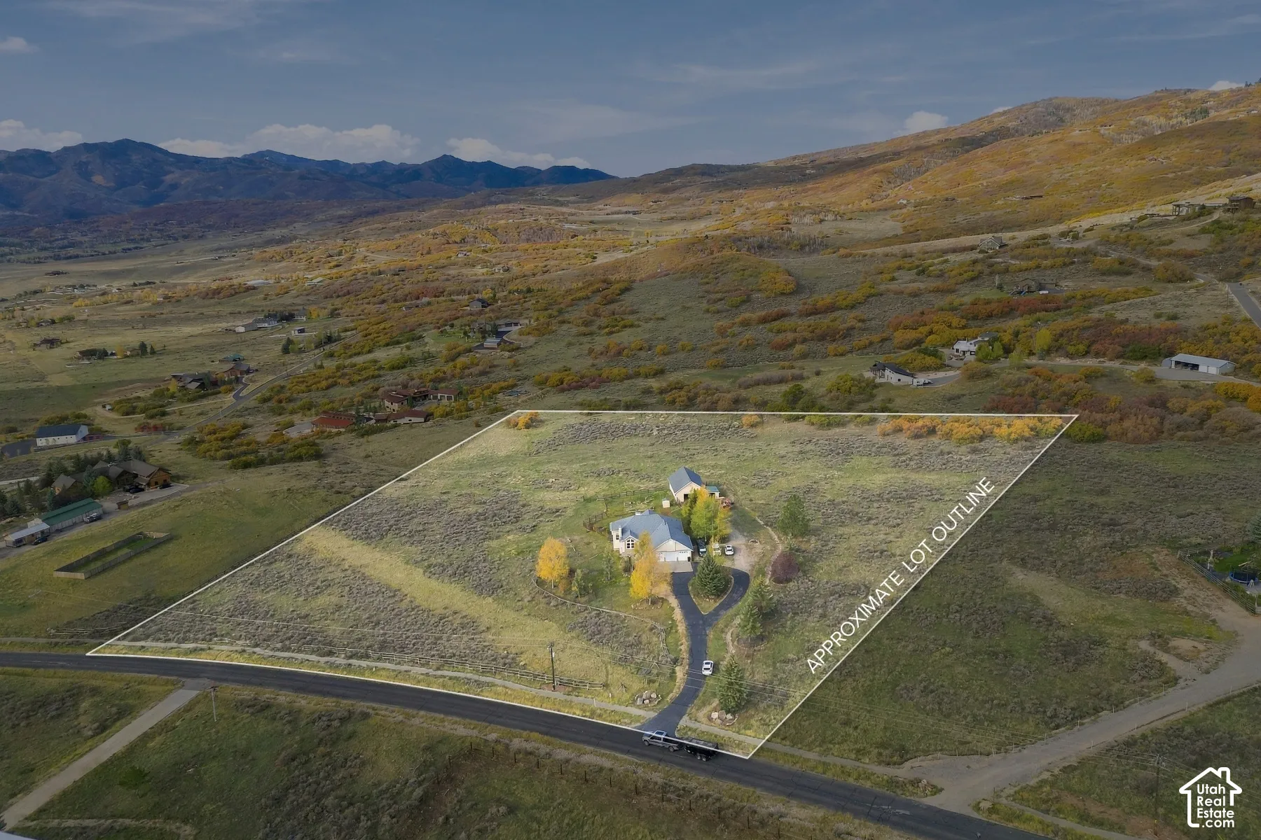 Expansive rural acreage featuring paved driveway access, detached auxiliary structure, and mountain backdrop