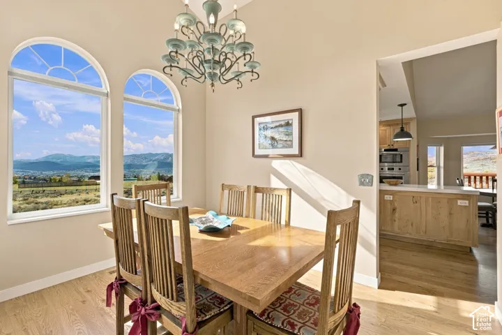 Dining area featuring arched windows with mountain scenery, wood-finish flooring, and a decorative multi-arm chandelier