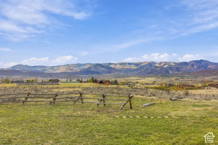 Open acreage featuring a post-and-rail timber fence and a mountain range backdrop