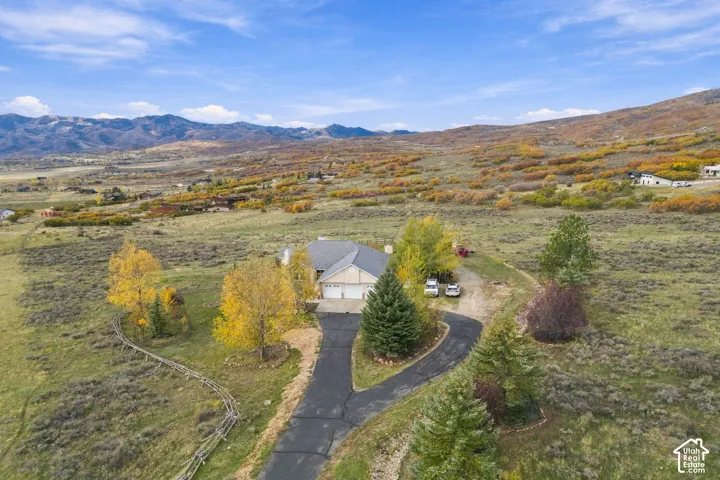Detached single-story residence featuring an asphalt driveway, multi-car garage, and mountain backdrop