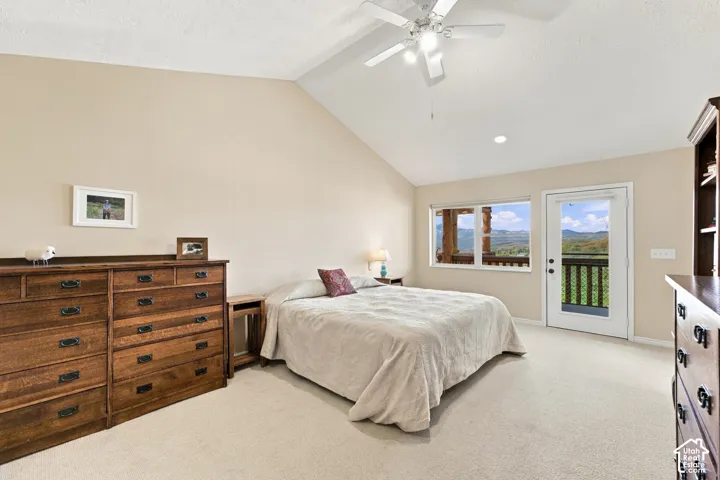 Vaulted ceilings, neutral wall tones, carpeted flooring, built-in shelving, and exterior access via a glass-paneled door