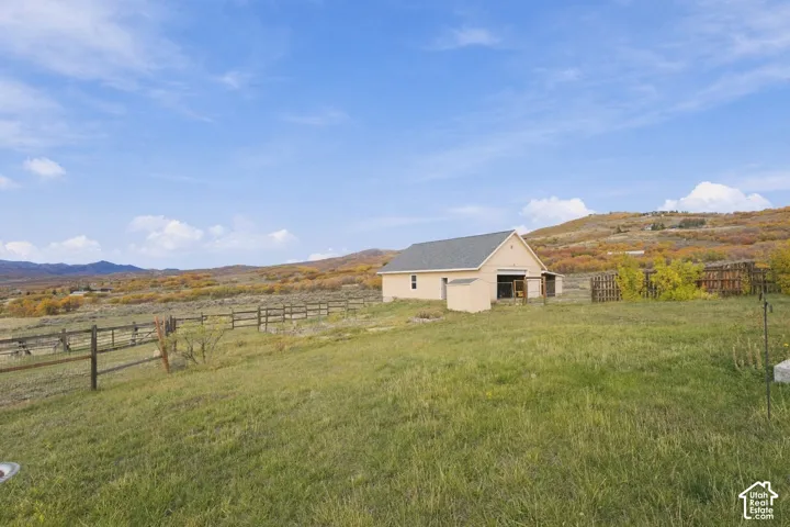 Open acreage featuring a detached outbuilding, split-rail fencing, and surrounding mountain topography