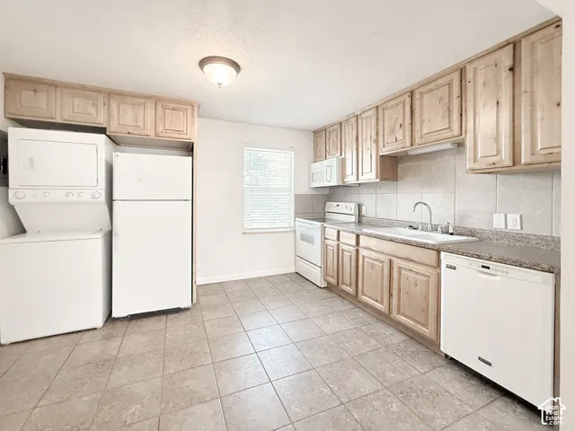 Kitchen featuring light wood cabinetry, stone-patterned laminate countertops, ceramic tile flooring, a dual-basin sink, and integrated laundry appliances