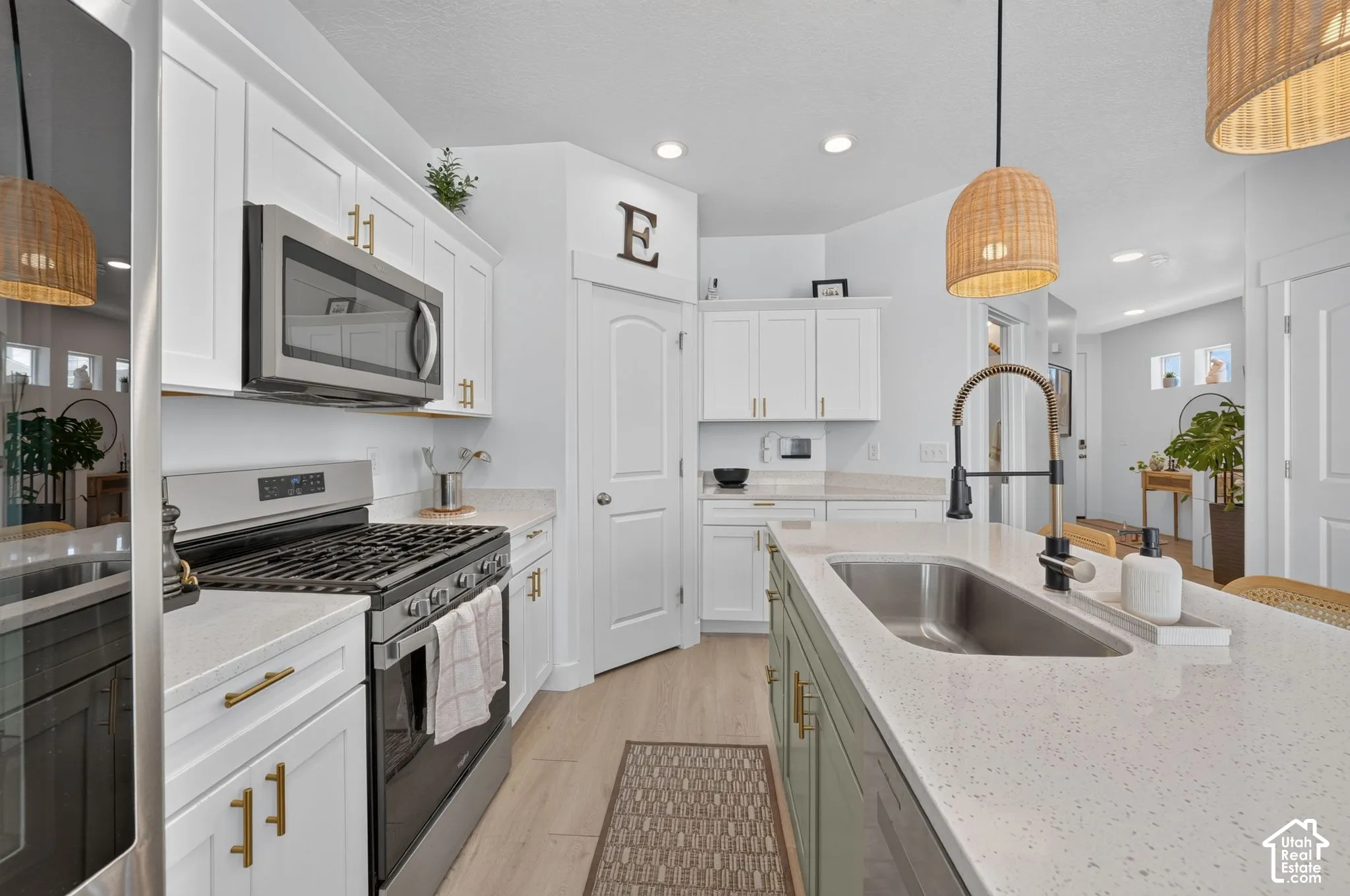 Kitchen featuring white cabinetry, solid-surface countertops, center island with undermount stainless steel sink, gas range, and recessed lighting