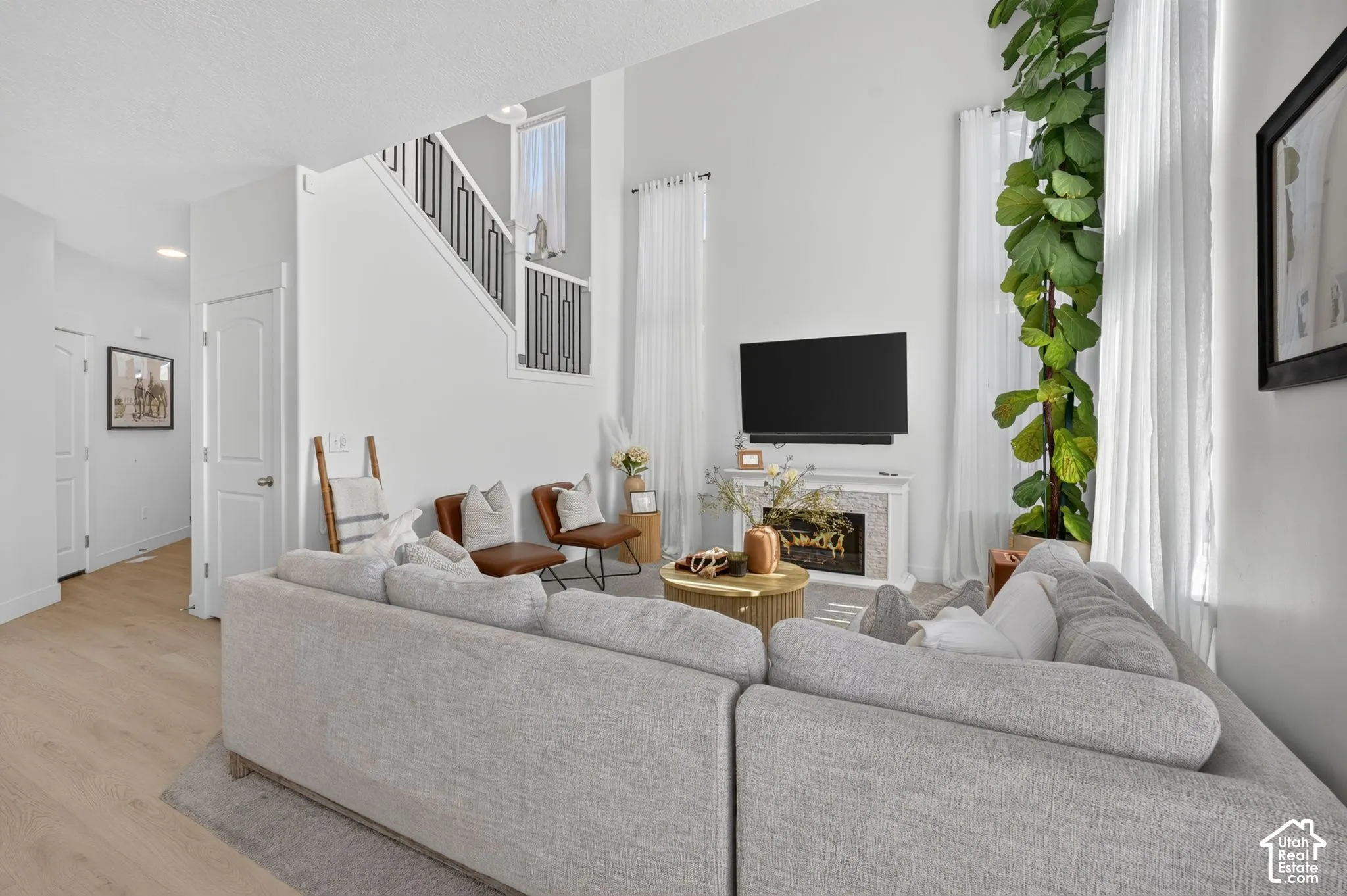 Living area featuring a double-height ceiling, fireplace with tiled surround, and wood-finish flooring