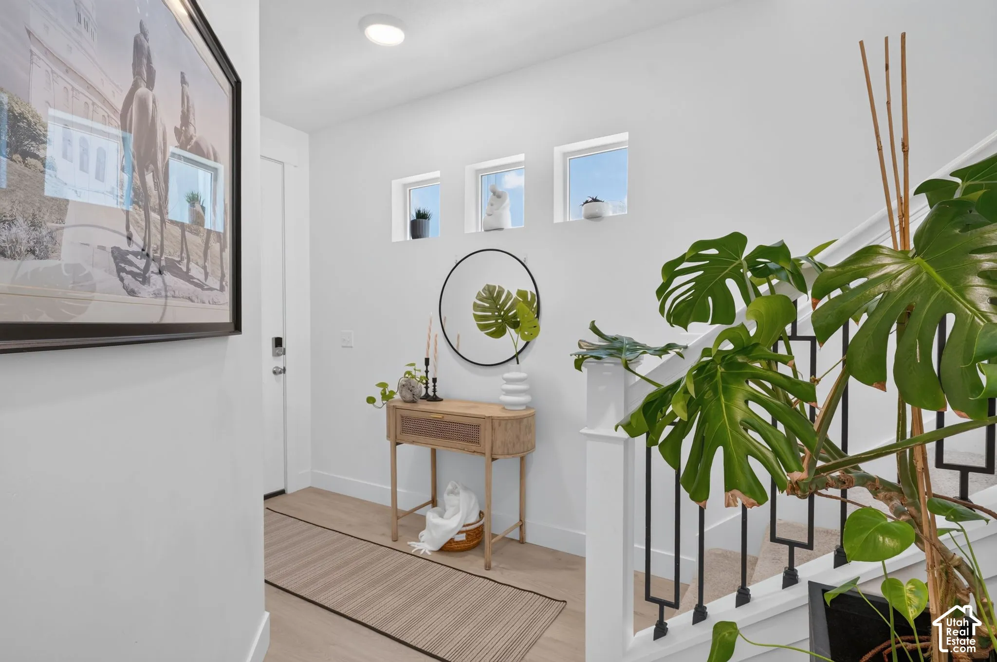 Entryway featuring three square transom windows, wood-finish flooring, and a staircase with white painted balusters and matte black metal spindles