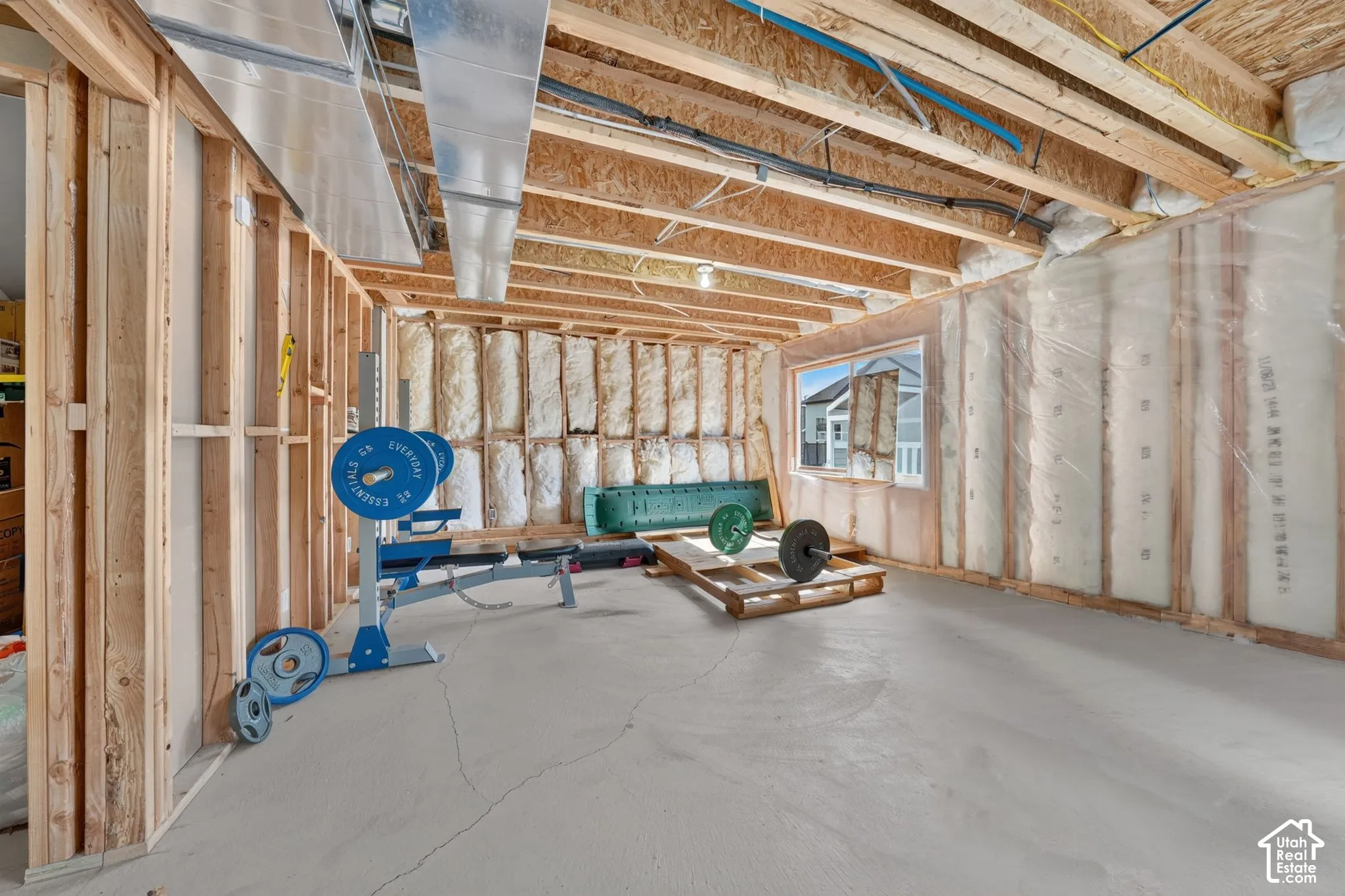 Unfinished interior space featuring exposed wood framing, batt insulation, concrete flooring, and an installed window
