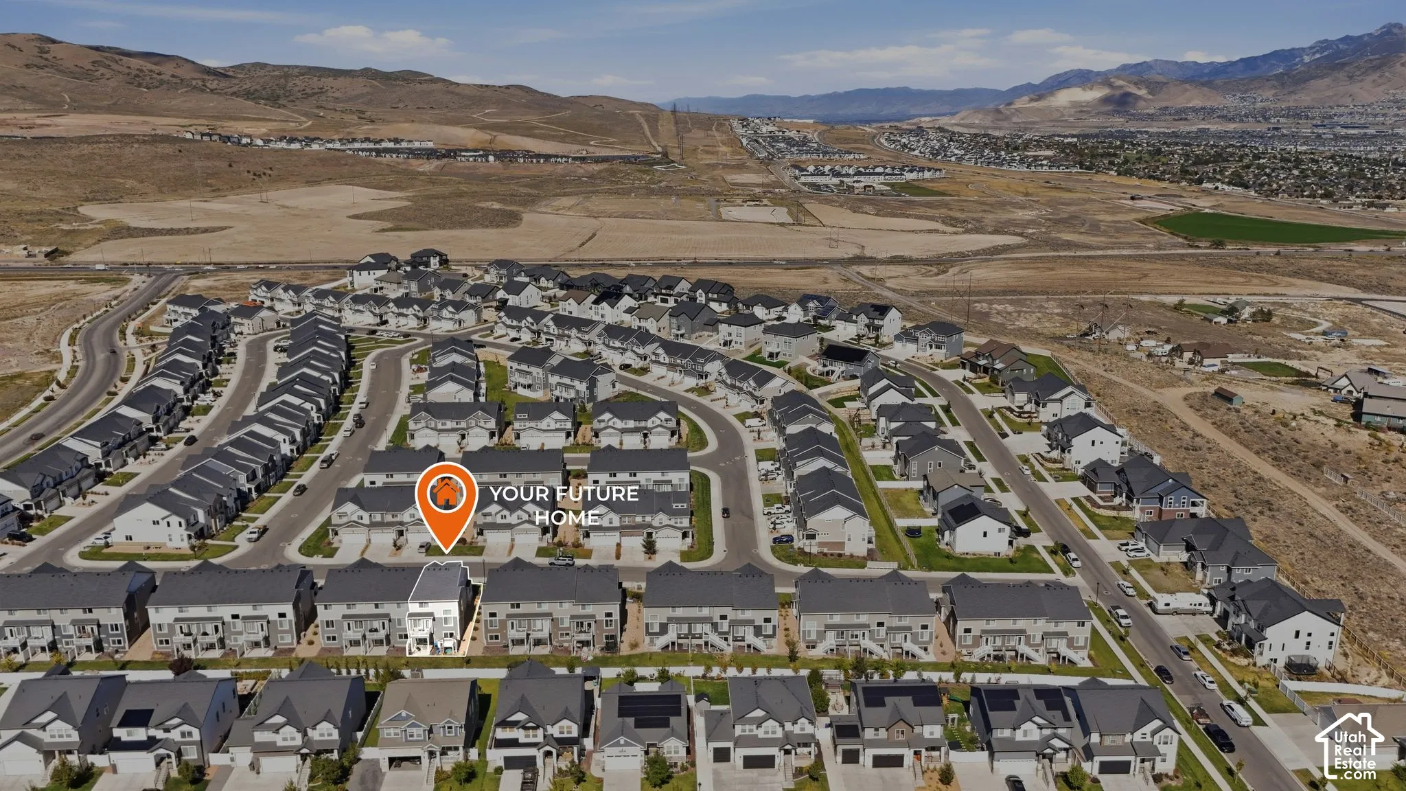 Aerial perspective featuring residential lots, paved infrastructure, and mountain terrain backdrop