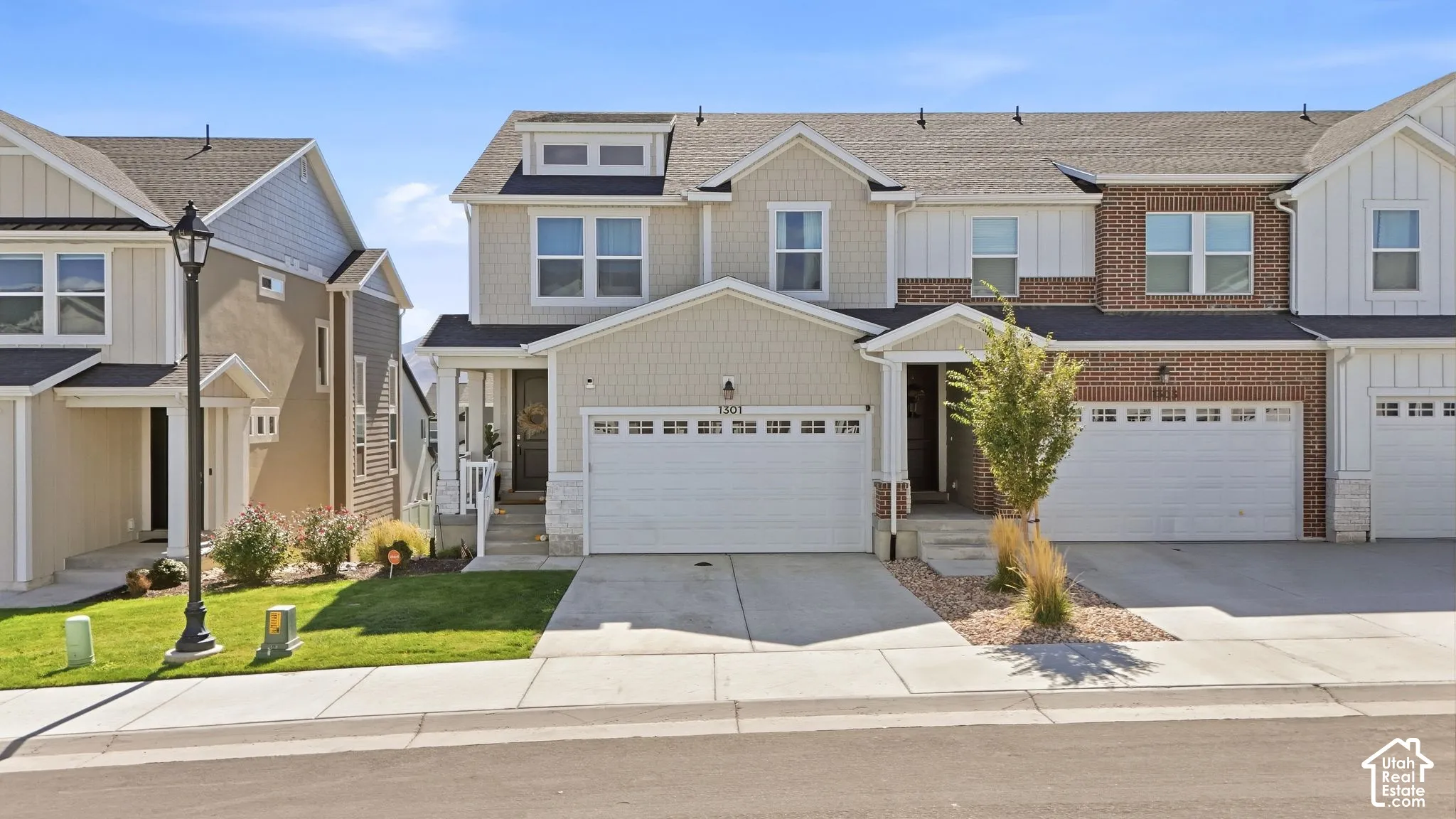Multi-level exterior featuring a brick and composite siding facade, double-pane windows, a gabled roofline, and an attached two-car garage