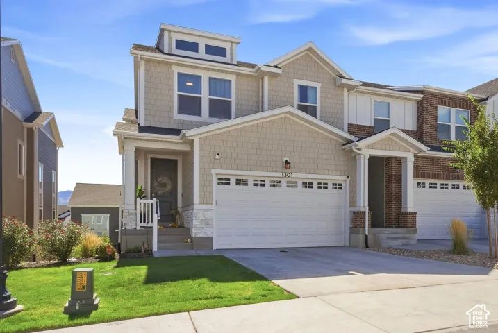 Multi-level exterior featuring a shingle-style facade, stone veneer accents, multi-pane window configuration, and a two-car garage