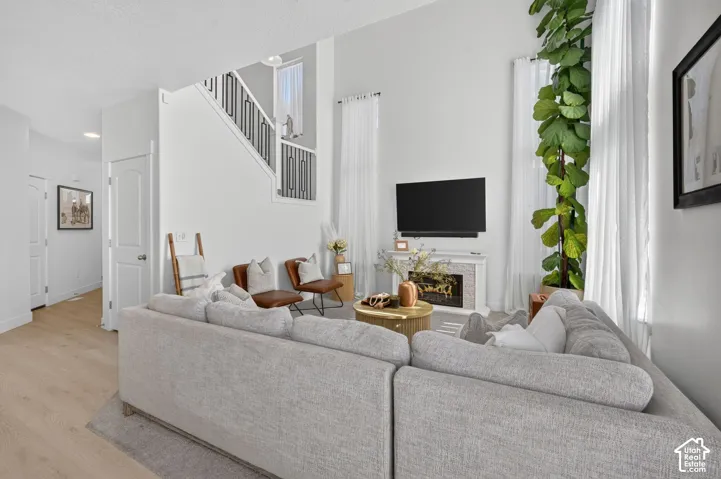 Living area featuring a double-height ceiling, fireplace with tiled surround, and wood-finish flooring