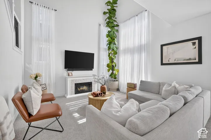 Living area featuring vaulted ceilings, floor-to-ceiling windows, and a fireplace with a textured surround