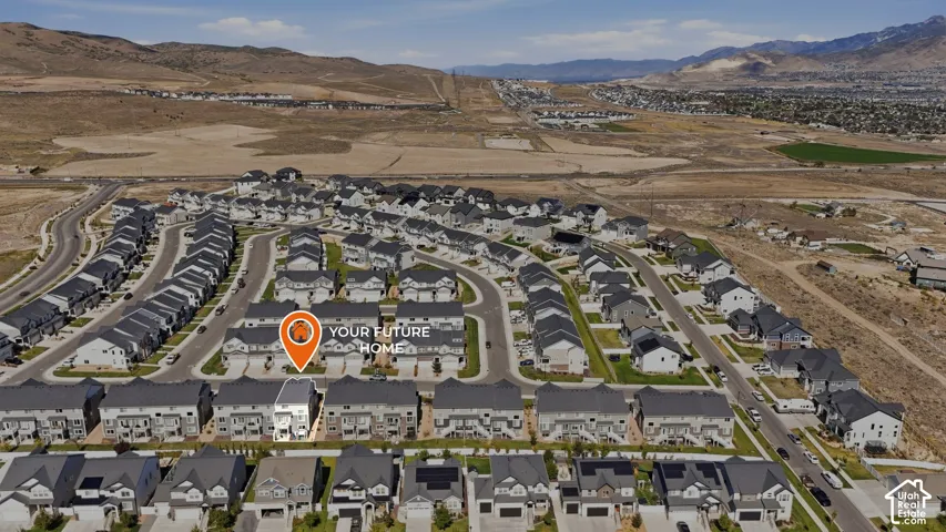 Aerial perspective featuring residential lots, paved infrastructure, and mountain terrain backdrop