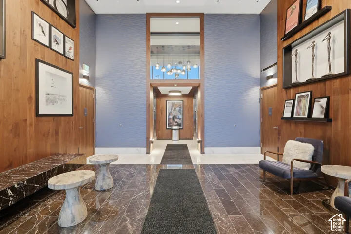 Grand entrance featuring high ceilings, stone flooring, wood-paneled walls, and built-in recessed display shelving