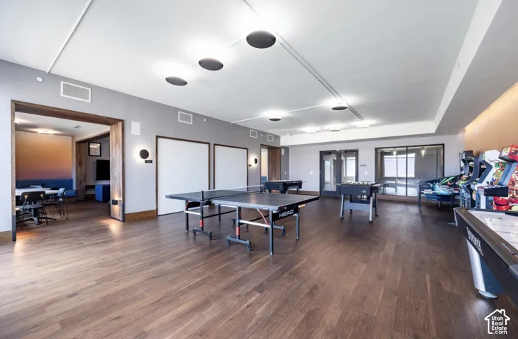 Open-concept recreational space featuring wood-finish flooring, recessed lighting, and wall-mounted sconces