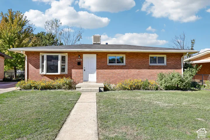 Red brick exterior featuring a multi-pane bay window, low-pitch roofline, and concrete front walkway
