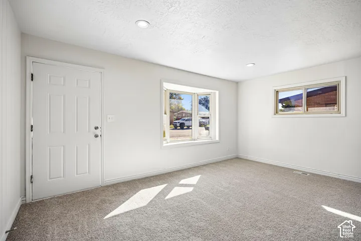 Interior space featuring wall-to-wall carpeting, recessed ceiling lighting, a prominent bay window, and a paneled exterior door