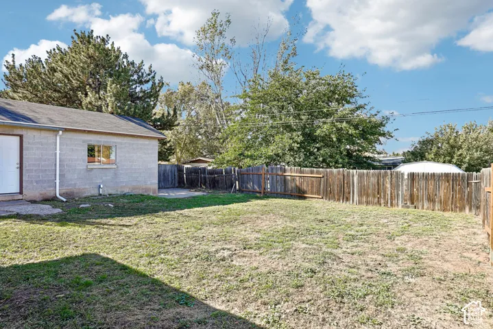 Rear exterior space featuring a block wall structure, a wood privacy fence, and mature trees