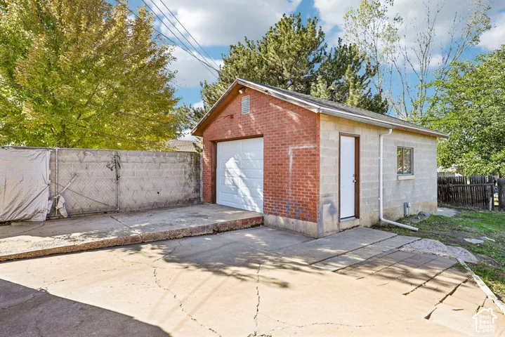 Detached garage featuring a brick and concrete block exterior, a single-car overhead door, a dedicated side-entry door, and a concrete driveway