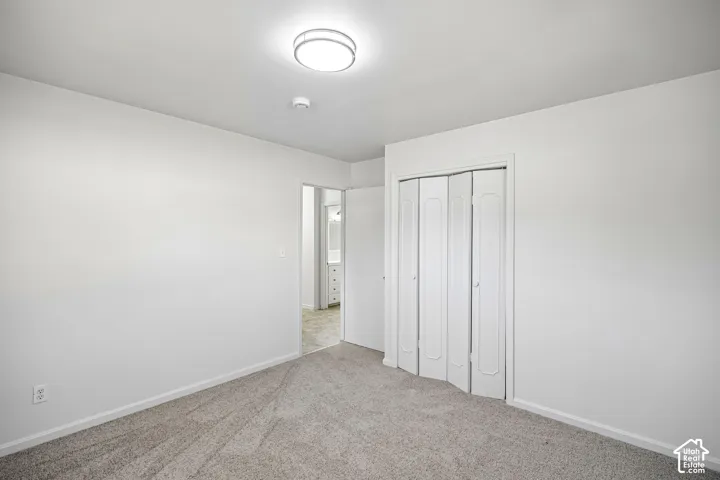 Neutral wall finishes, plush carpeting, ceiling-mounted light fixture, and bi-fold closet doors
