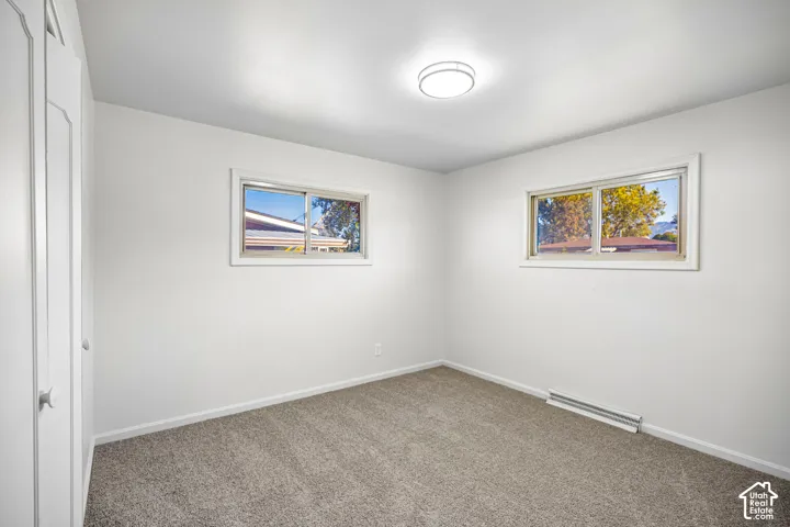 Neutral-toned wall-to-wall carpeting, dual sliding windows, built-in closet with doors, and flush-mount ceiling lighting