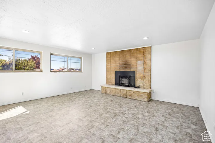 Open living space featuring tile flooring, recessed lighting, and a floor-to-ceiling textured tile fireplace surround with a raised hearth and integrated insert