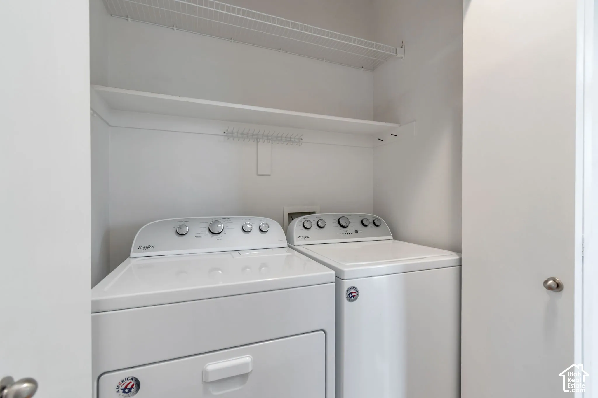 Laundry closet featuring a pair of top-load washer and dryer units, a fixed wood shelf, and an overhead wire storage rack