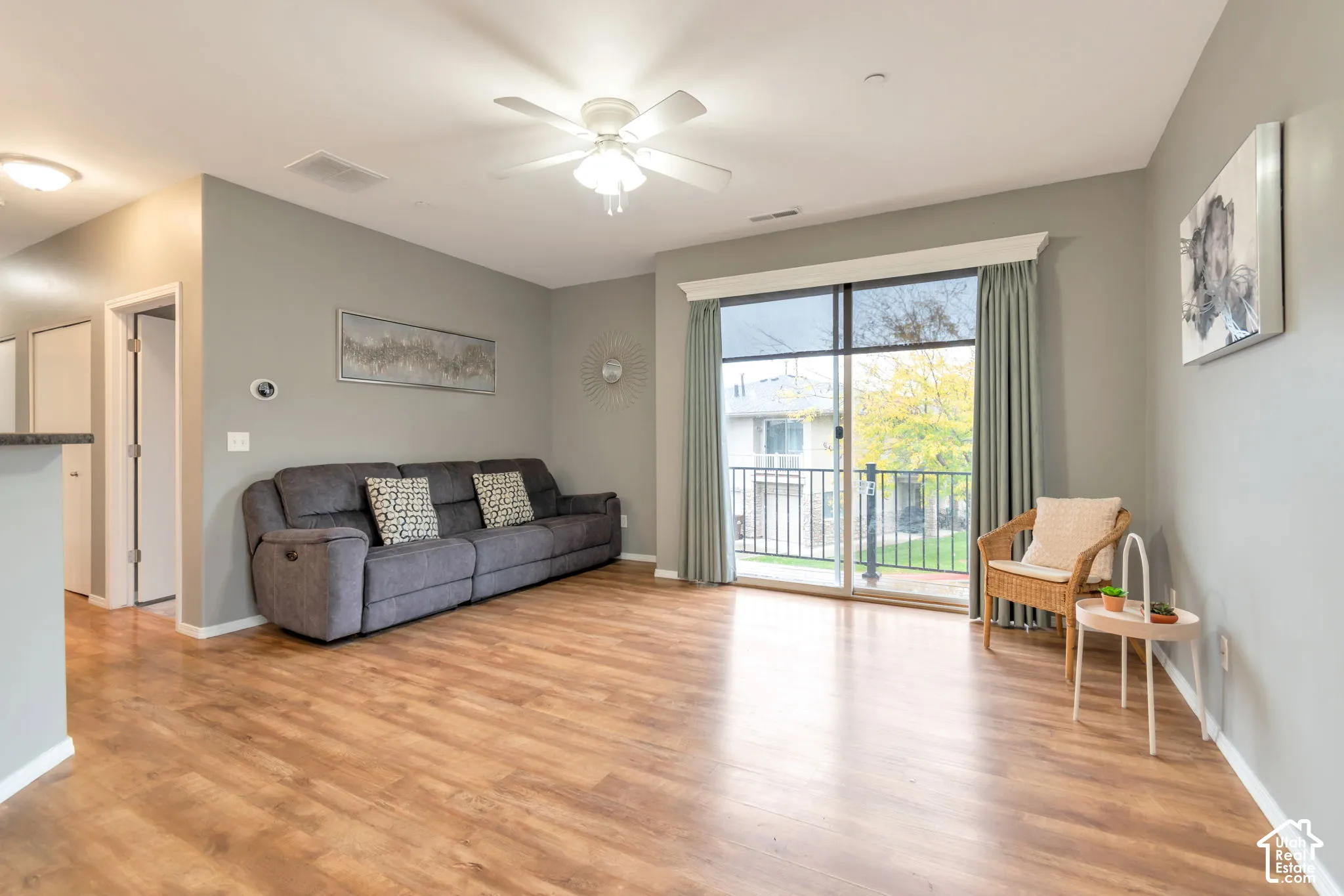 Wood-finish flooring, ceiling fan with integrated lighting, and glass sliding doors with access to a railed balcony